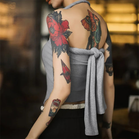Person with tattoos on arms and back wearing a gray apron.